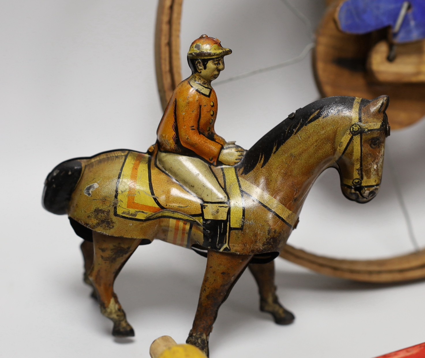 A Victorian carved pine jointed peg doll, jointed wood uni-cyclist toy, two abacuses and an early 20th century German tin plate and clockwork jockey on racehorse